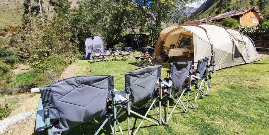 luxury dining tent campsite luxury inca trail for families Luxury dining tent setup on the Luxury Inca Trail for Families, featuring comfortable chairs, cushions, and elegant tableware.